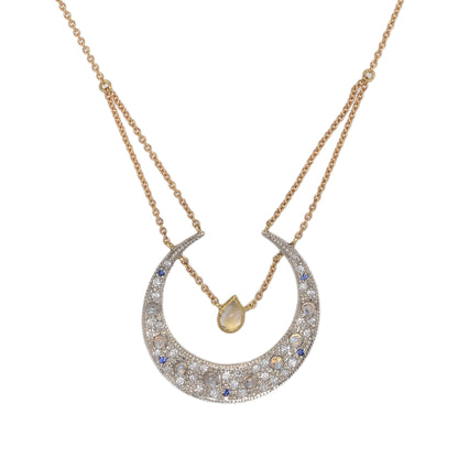 Selene Diamond Crescent Moon Necklace by Unhada. The Selene Diamond Moon Necklace is aptly named after the Greek goddess and features a sterling silver pendant encrusted with .34 cts of diamonds, complemented by blue sapphires and faceted rainbow moonstones. Adding to its elegance, a single pear-cut labradorite rests at the center of the crescent, suspended from an 18k yellow gold chain. The necklace can be adjusted to a length of 16 - 18" making it perfect for layering with other pieces.