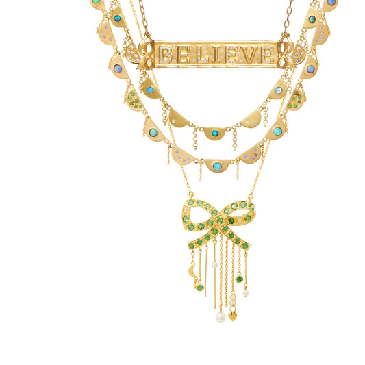 Shelley Bow Necklace by Unhada - Feminine and playful, the one-of-a-kind Shelley Bow Necklace exudes coquettish charm. Handcrafted in 18k gold, the bow is encrusted with vibrant tsavorite (1.17 cts) and opals (.27 cts). The cascading chain fringe adds flirty movement and is accented with a tiny crescent moon, diamonds (.05 cts), and pearls. Adjustable length 17-19", with a lobster clasp for a secure fit.