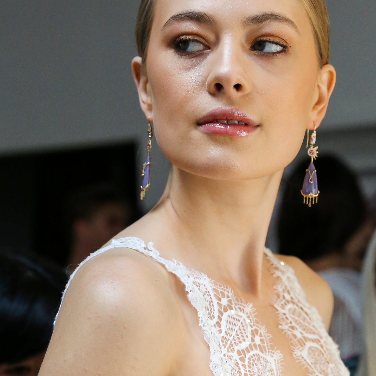 Woman in a white lace dress holding a phone with a blurred background